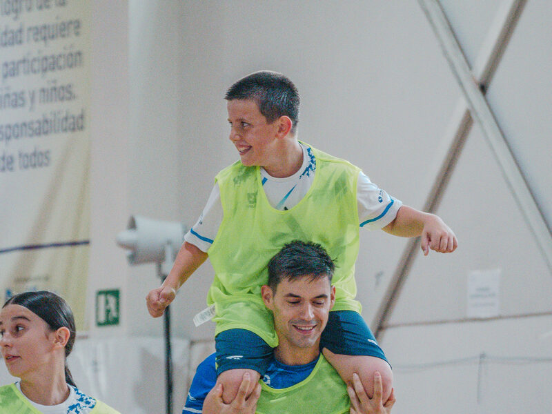 Entrenador llevando a un joven a hombros durante una actividad